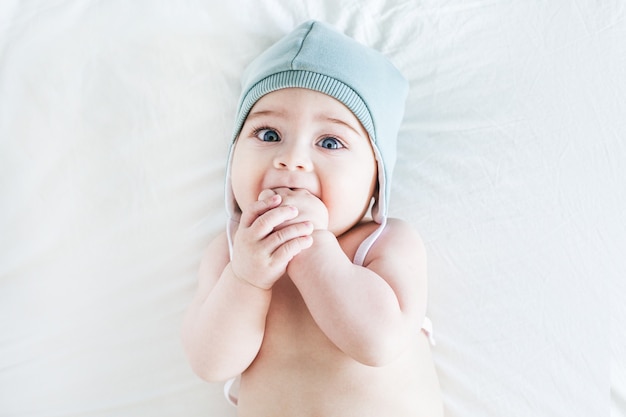 Niño recién nacido desnudo con gorro en la cama