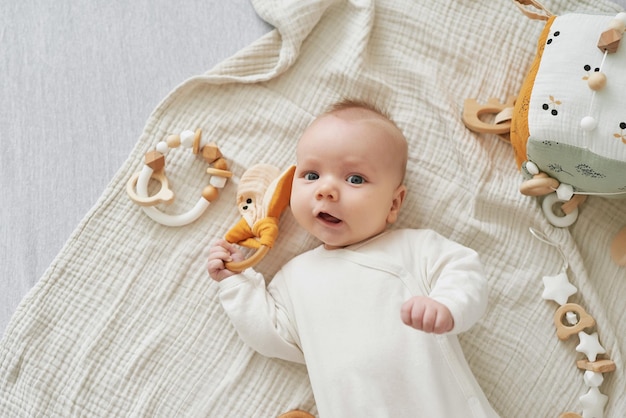 Niño recién nacido miente y juega con juguetes educativos. Feliz maternidad y paternidad. Maternidad y clínica. Día del padre y de la madre. El desarrollo de la primera infancia.