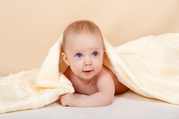 Niño recién nacido que se relaja en la cama después del baño o la ducha. Concepto de infancia