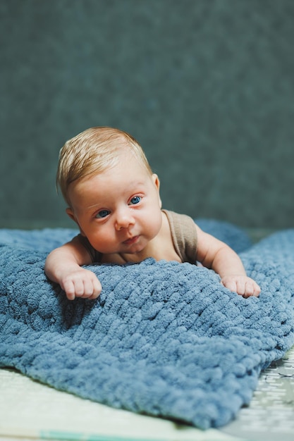 Un niño recién nacido yace sobre una manta de punto gris Retrato de un bebé de un mes de edad