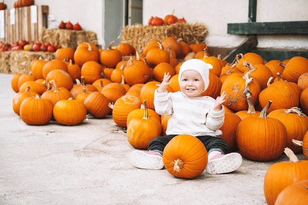 Niño recogiendo calabazas en el huerto de calabazas Niña pequeña jugando entre calabazas en el mercado agrícola