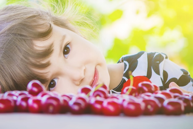 Foto el niño está recogiendo cerezas en el jardín. enfoque selectivo