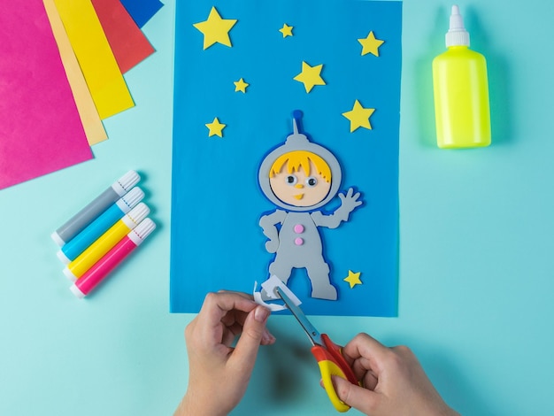 El niño recorta el papel astronauta y estrellas.