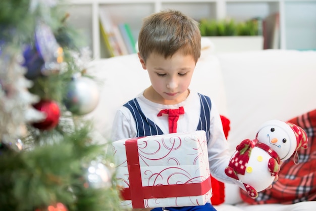 Un niño con un regalo de Navidad. Obtenga un regalo para Navidad. El niño recibió un regalo