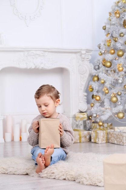 Niño con regalos bajo el árbol de Navidad