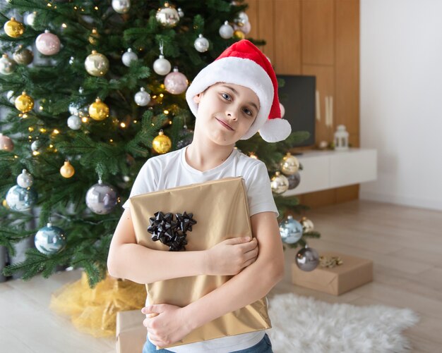 Niño con regalos juega cerca del árbol de Navidad. Interior de la sala de estar con árbol de Navidad y adornos. Año nuevo. Dar regalos.