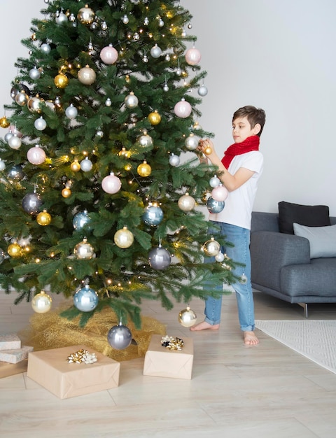 Niño con regalos juega cerca del árbol de Navidad. Interior de la sala de estar con árbol de Navidad y adornos. Año nuevo. Dar regalos.