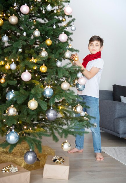 Niño con regalos juega cerca del árbol de Navidad. Interior de la sala de estar con árbol de Navidad y adornos. Año nuevo. Dar regalos.