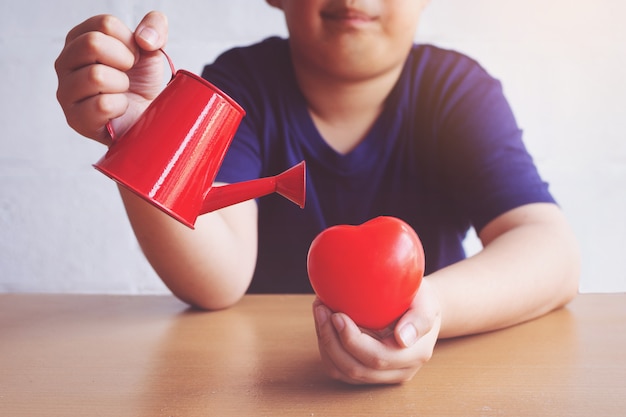 Niño regando el corazón rojo. enamorado