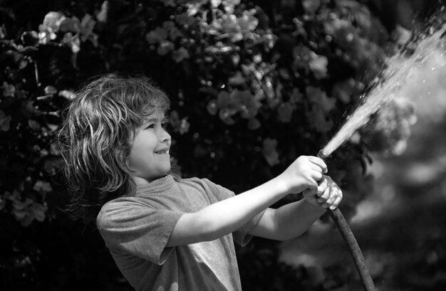 Niño regando plantas en el jardín el concepto de bondad infantil y la infancia pequeño ayudante rubio encantador