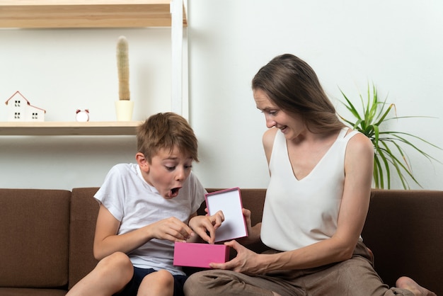 El niño se regocija con el regalo de su madre. Regalo para hijo. El niño tiene un regalo.