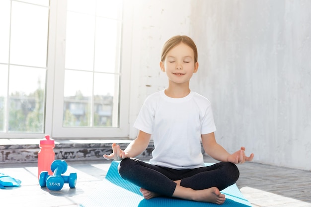 Niño relajado manteniendo los ojos cerrados mientras hace yoga en el suelo