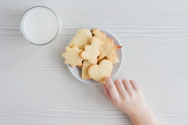 Un niño roba de un plato de galletas caseras recién horneadas