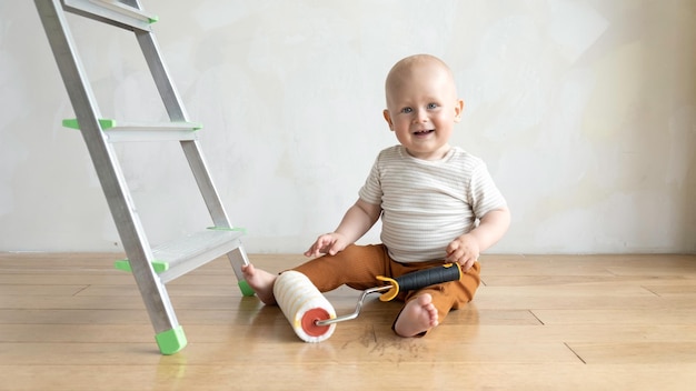 Niño con rollo de pintura cerca de la escalera y la pared de pintura Copyspace Wallpaper accesorios de pegado herramientas de pintura ad Reparación del hogar concepto de renovación de la construcción de la casa Infancia de la paternidad