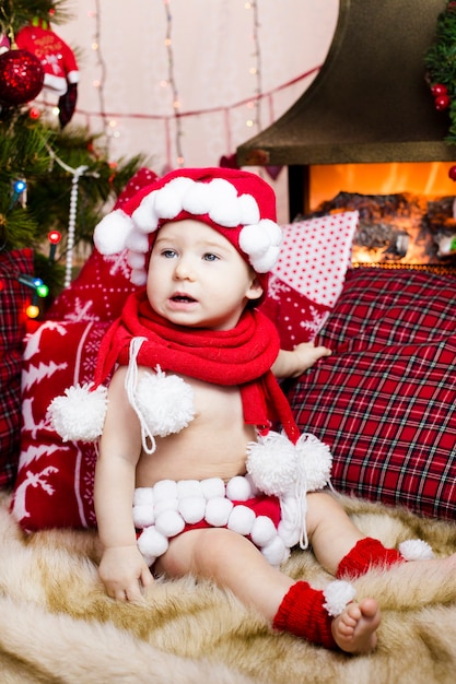 Niño con ropa de año nuevo, pasa tiempo en el árbol de Navidad