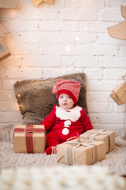 Niño con ropa de año nuevo, pasa tiempo en el árbol de Navidad