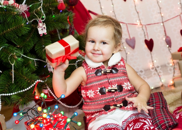 Niño con ropa de año nuevo, pasa tiempo en el árbol de Navidad