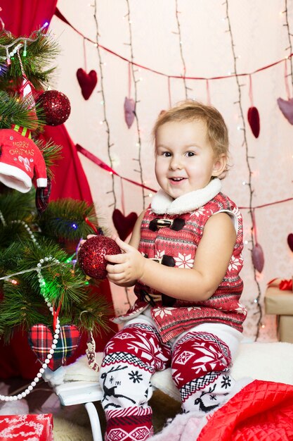 Niño con ropa de año nuevo, pasa tiempo en el árbol de Navidad
