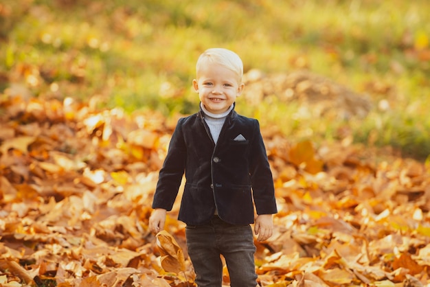 Niño en ropa de chaqueta de otoño. Niño con hoja amarilla en el parque otoño.