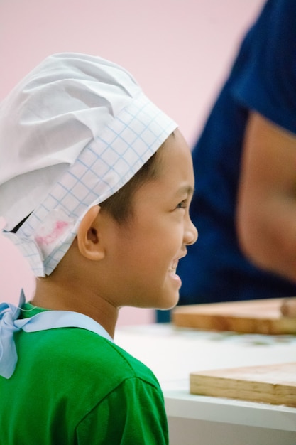 Un niño con ropa de cocina se divierte aprendiendo a cocinar.