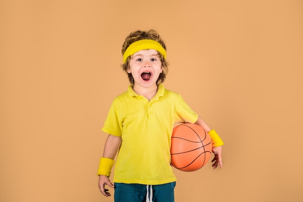 Niño en ropa deportiva lanza bola lindo niño tiene pelota de baloncesto adorable niño jugando