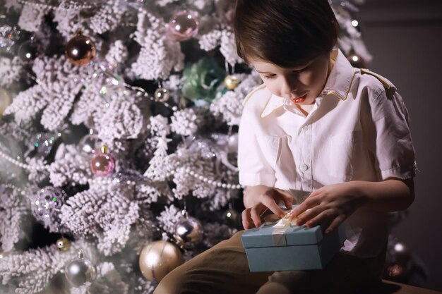Niño con ropa elegante frente al árbol de Navidad. Vispera de Año Nuevo. Esperando el nuevo año.