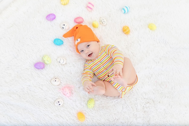 Niño en ropa naranja con huevos de Pascua, lindo bebé sonriente divertido. El concepto de Pascua.