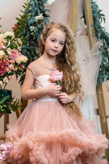 Un niño con una rosa en un vestido de color rosa sostiene una flor flores felices niño pequeño