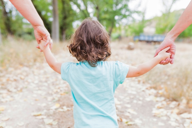 Foto niño sin rostro caminando con los padres