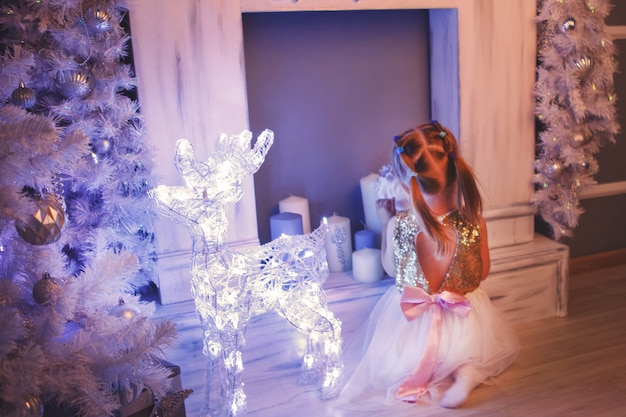 Niño rubio con un árbol de Navidad. Lujosa decoración navideña.