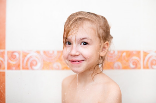 Niño rubio en el baño debajo de la ducha.