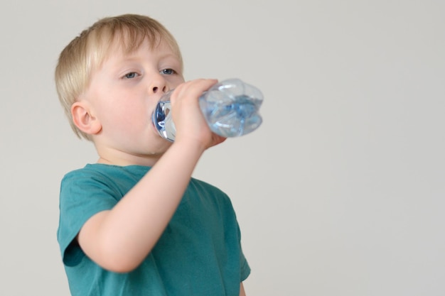 niño rubio bebe agua