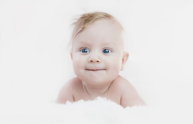 Niño rubio de cinco meses con ojos azules se acuesta boca abajo, sonriendo lindo,