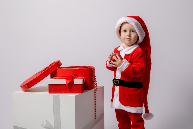 niño rubio en un disfraz de Papá Noel sobre un fondo blanco