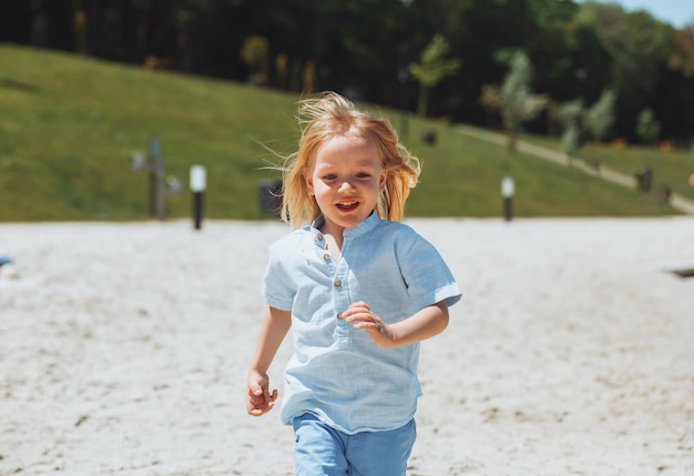 Un niño rubio feliz corre y se divierte en la playa