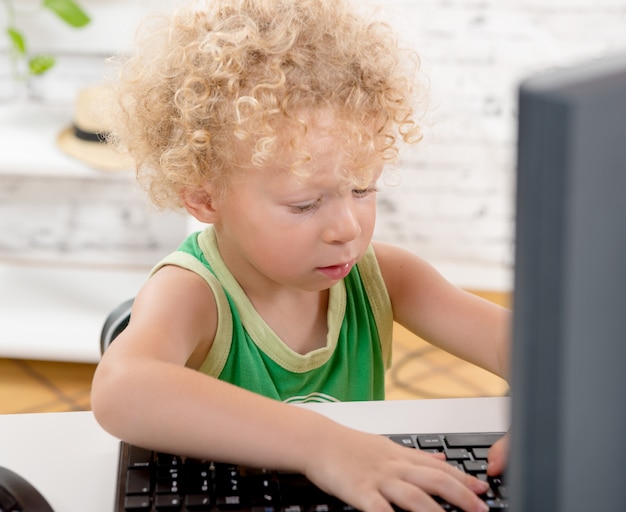 Un niño rubio jugando con el teclado de una computadora