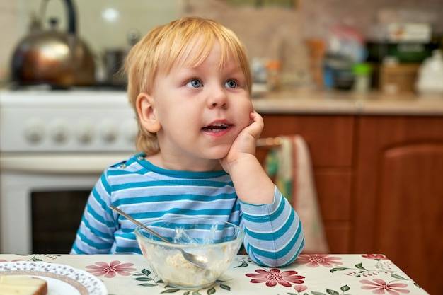 Niño, rubio con ojos azules de tres años, desayunó y se ensució la cara