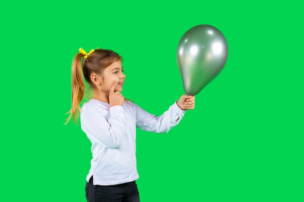 Niño rubio pensativo con coletas mira un globo gris definitivo