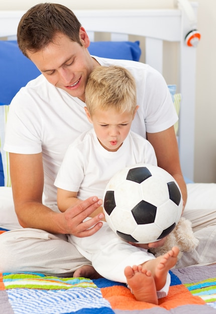 Niño rubio y su padre jugando con un balón de fútbol