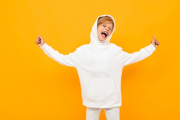 niño rubio con una sudadera con capucha blanca gritando en voz alta en naranja