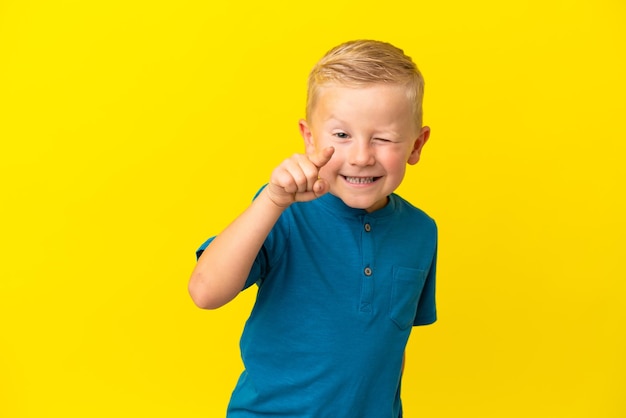 Un niño ruso aislado de fondo amarillo apuntando al frente con expresión feliz