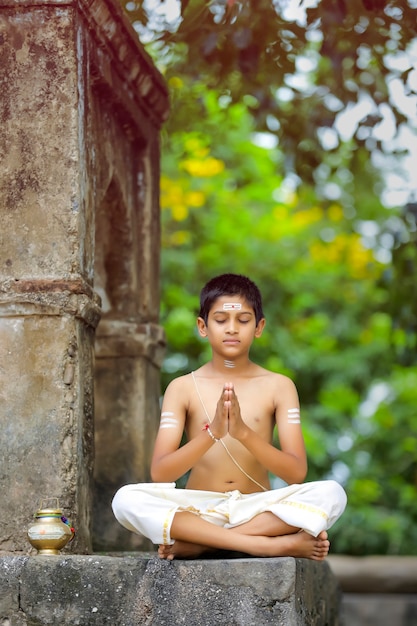 El niño sacerdote indio haciendo meditación