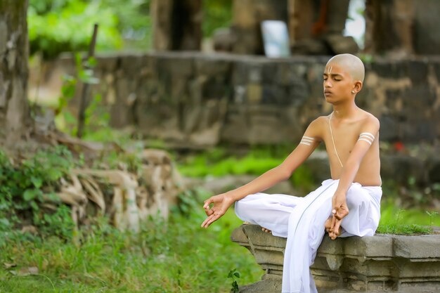 Niño sacerdote indio haciendo yoga en el parque