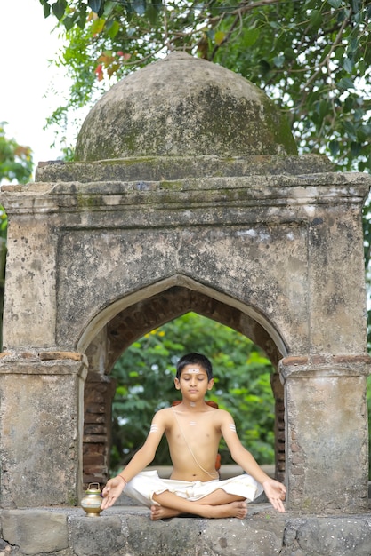 Niño sacerdote indio haciendo yoga en el parque