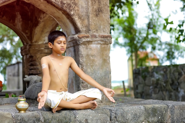 Niño sacerdote indio haciendo yoga en el parque