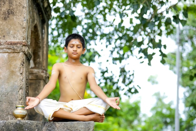 Niño sacerdote indio haciendo yoga en el parque