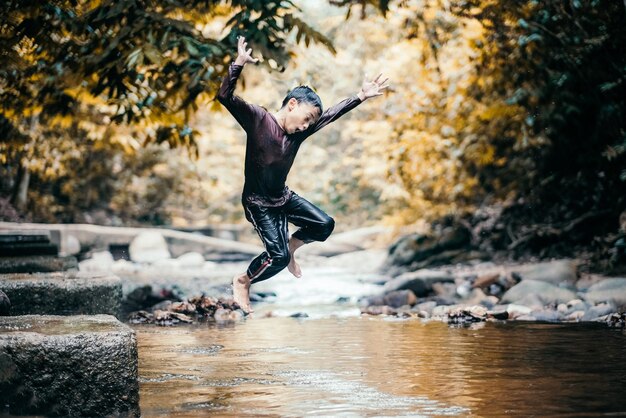 Foto niño saltando al lago en el bosque