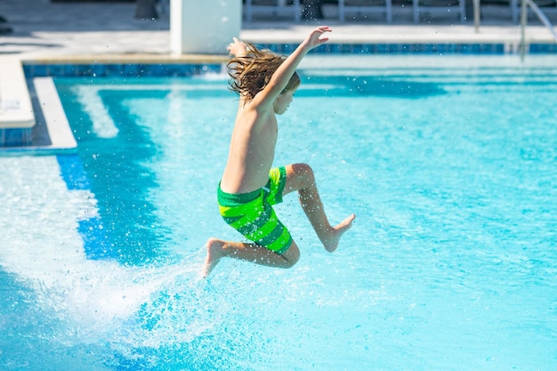 Foto niño saltando en la piscina de agua niño disfrutando de las vacaciones de verano nadando en la piscina niño divirtiéndose en vacaciones de verano