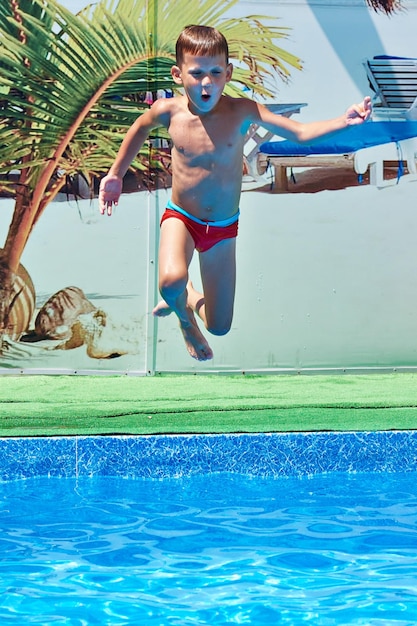 Foto niño saltando a la piscina del resort