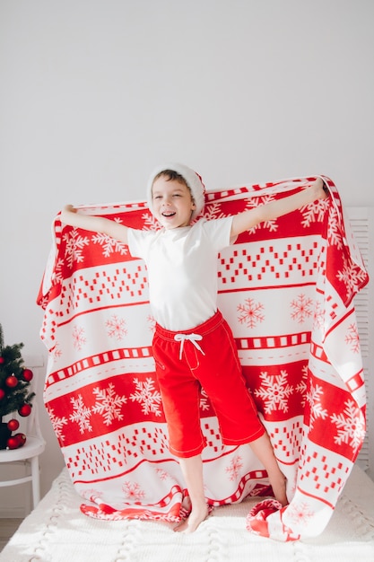 Foto niño saltando sobre la cama cubierta con una manta